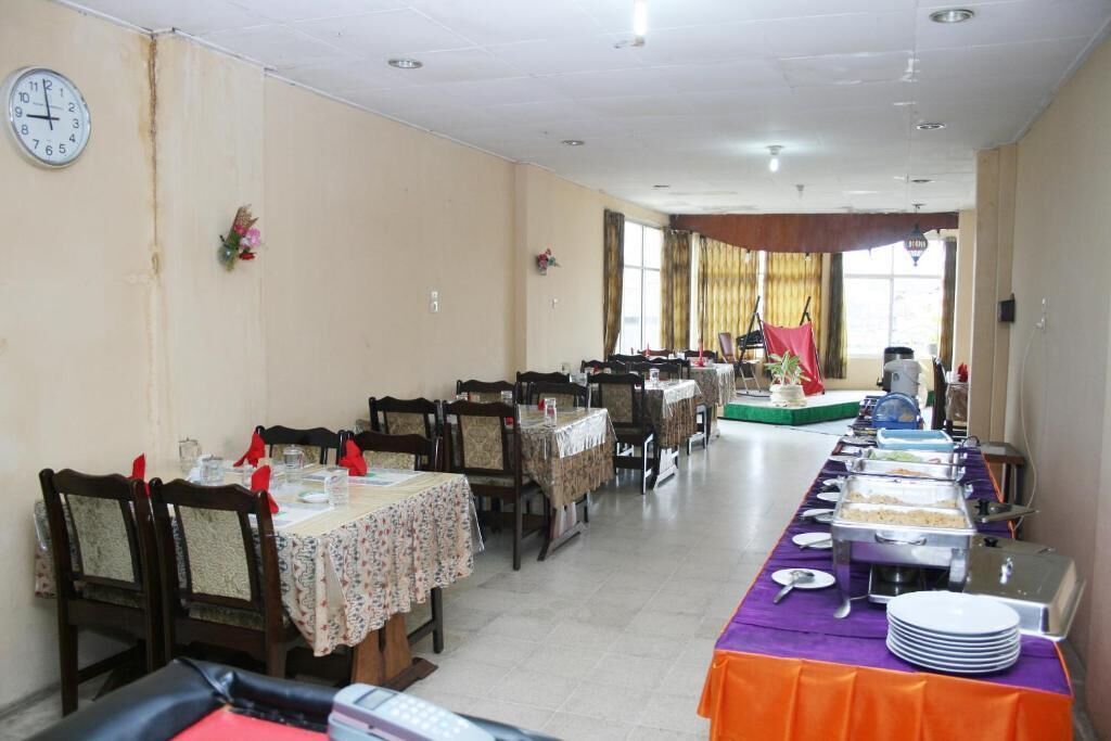 A dining hall with multiple tables, chairs, and a buffet line with various food items.