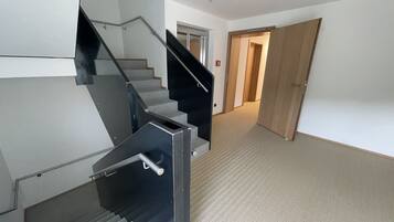 Un interior moderno con una escalera, pisos alfombrados y una puerta de madera.