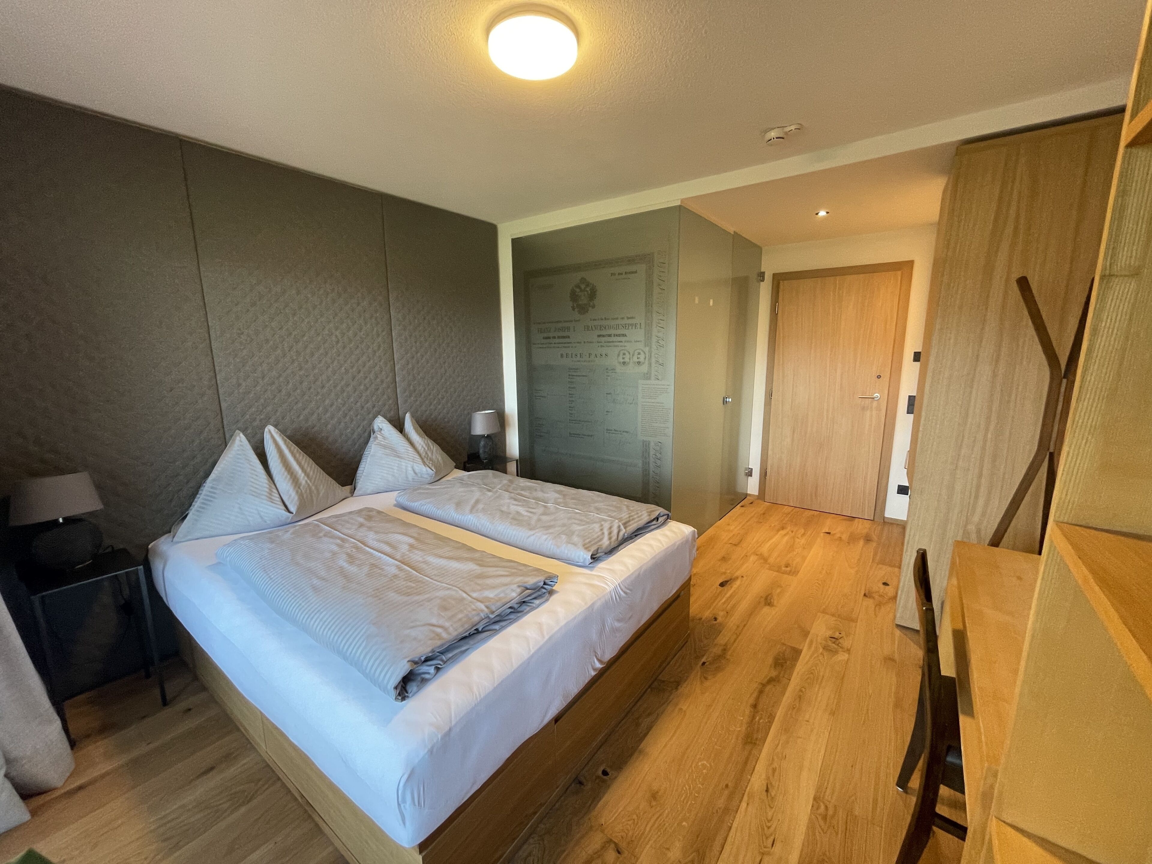 Ein Doppelbett mit Holz Kopfteil, ein Nachttisch mit Lampe und Holzboden.