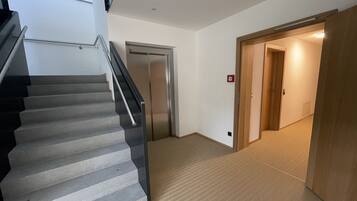 A staircase leading to a door, carpeted floor, and a hallway with a wooden door.