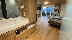 Un baño moderno con un espejo grande, armarios de madera y un lavabo empotrado.