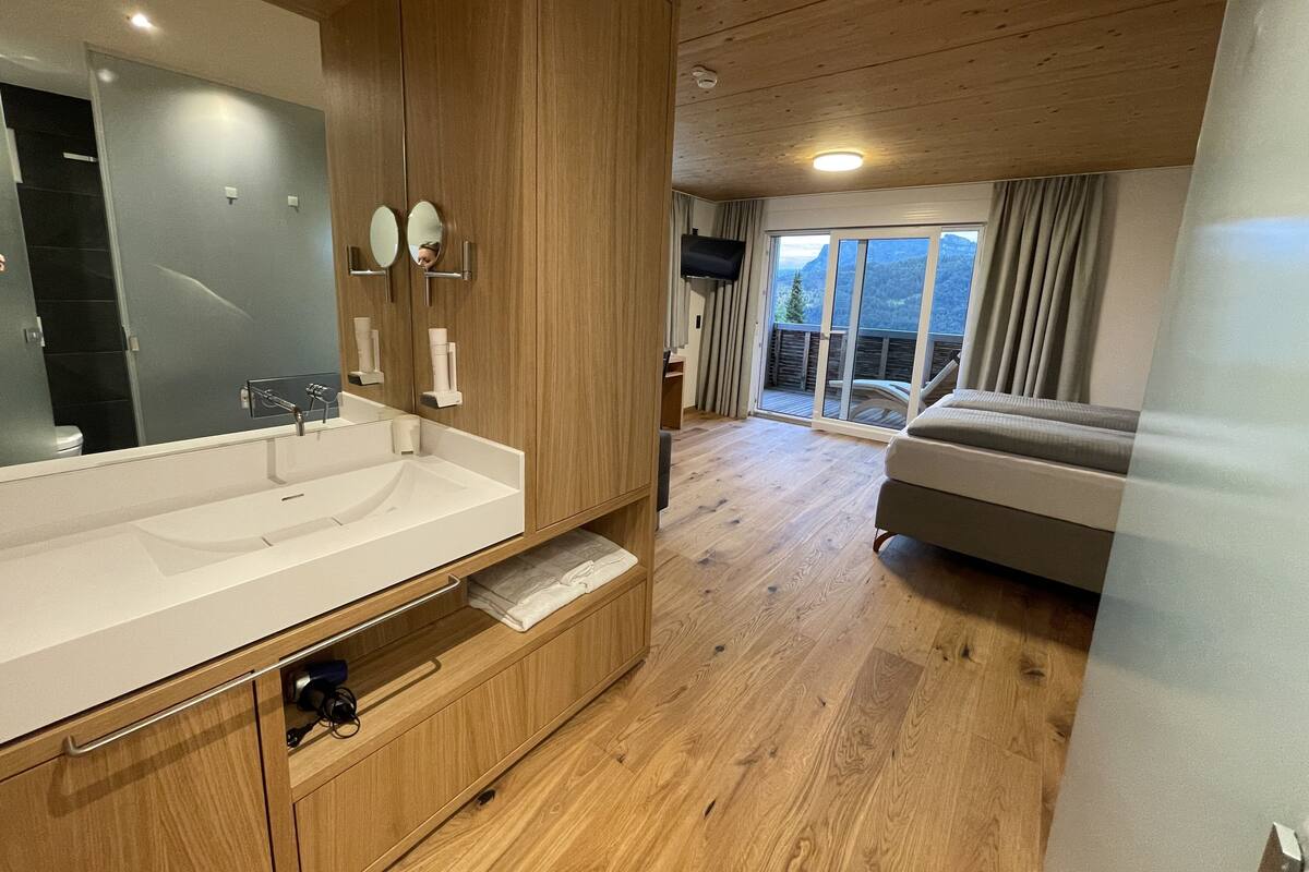 A modern bathroom with a large mirror, wooden cabinets, and a built-in sink.