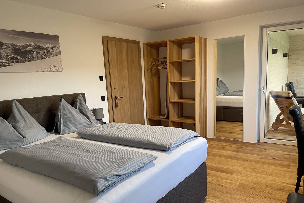 A bedroom with a bed, a wardrobe, and a mirror.