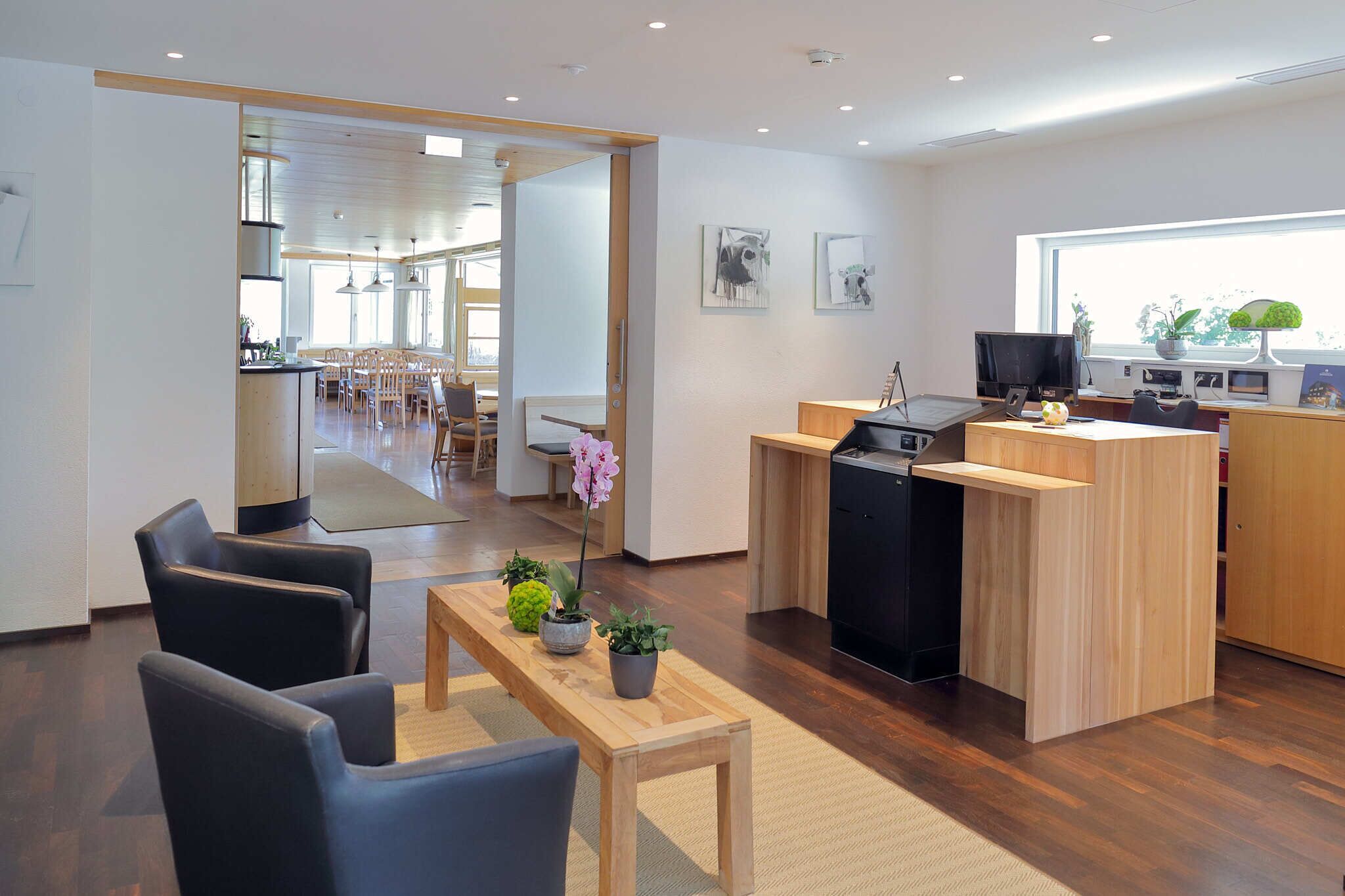 A modern kitchen with a dining area, wooden furniture, and a large window providing natural light.