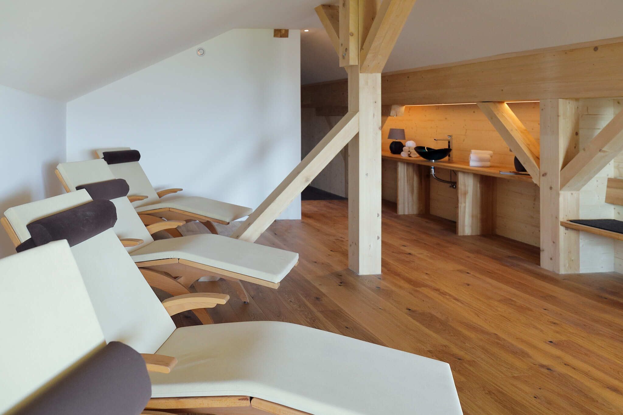 Ein Zimmer mit Holzboden, einer Treppe und einer Sitzecke mit Sesseln.