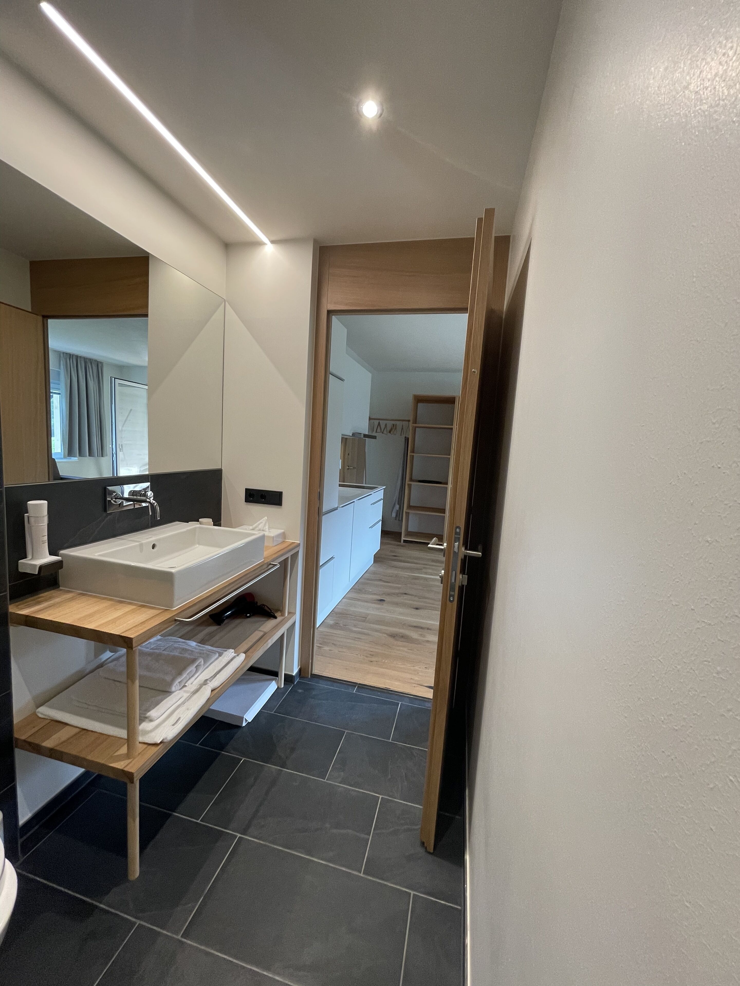 Un baño moderno con un lavamanos grande, tocador de madera y un espejo.