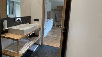 Een moderne badkamer met een groot wastafel, houten wastafelmeubel en een spiegel.