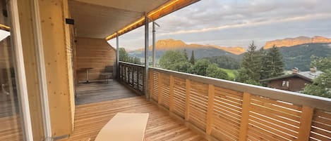 Una terraza de madera con vistas a montañas y un cielo despejado.