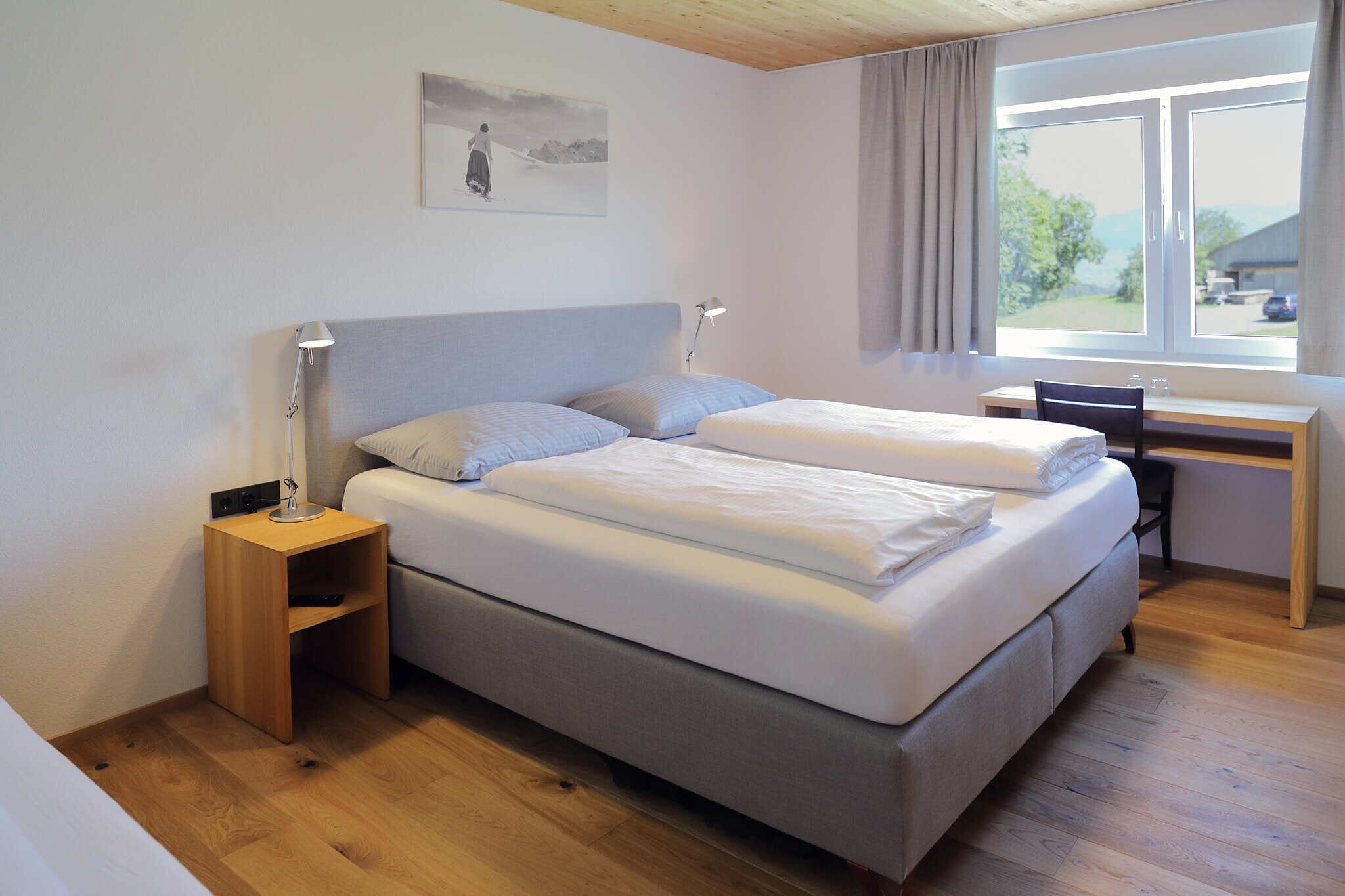 A bedroom with a bed, bedside tables, a desk, and a window.