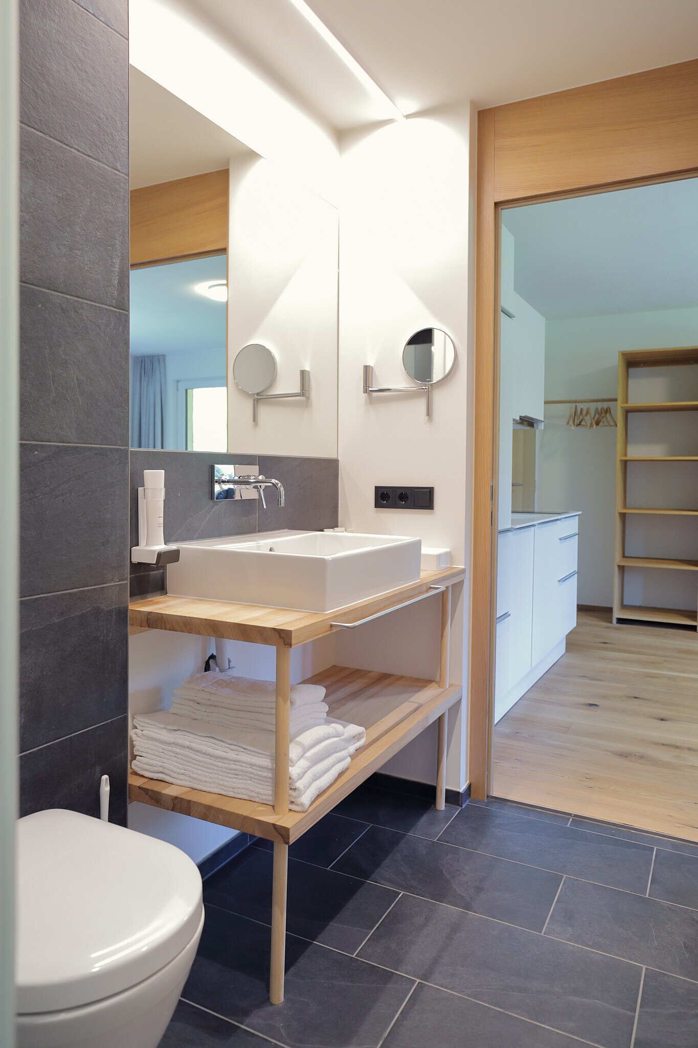 A modern bathroom with a white sink, mirror, and towel rack.