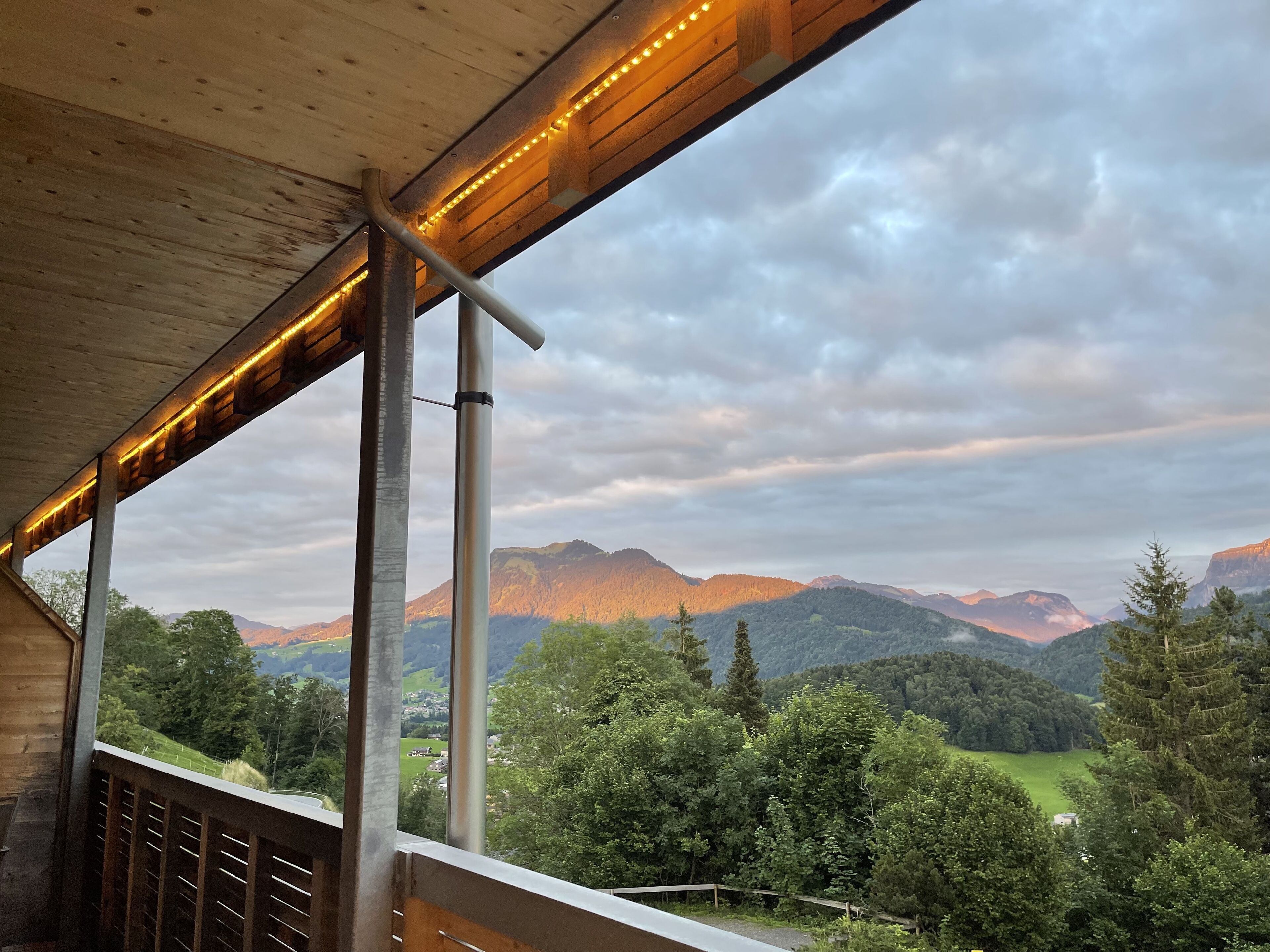 Un balcon en bois offrant une vue sur un paysage montagneux.