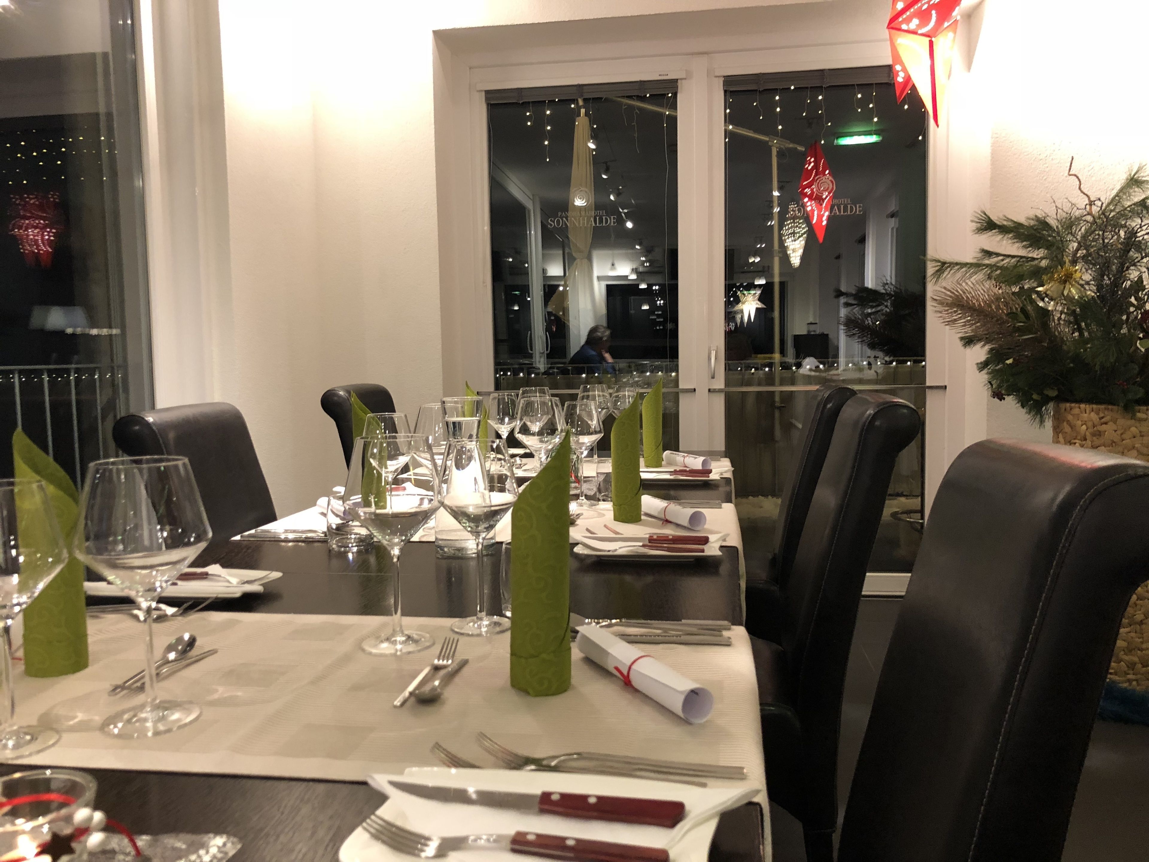 A dining table set for a meal with multiple wine glasses, cutlery, and napkins.