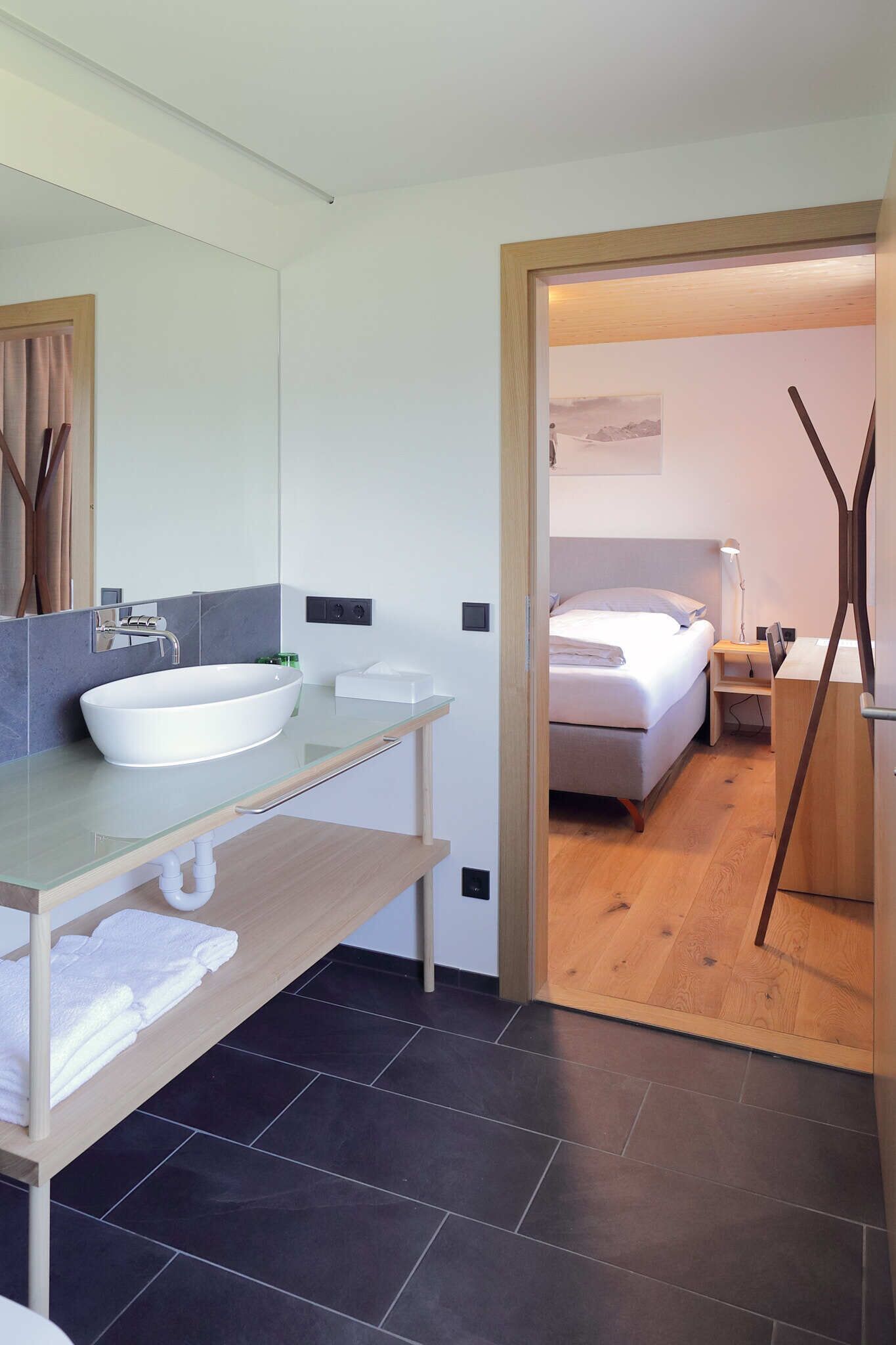 Un bagno moderno con un ampio lavandino bianco, uno specchio e un mobile bagno in legno.