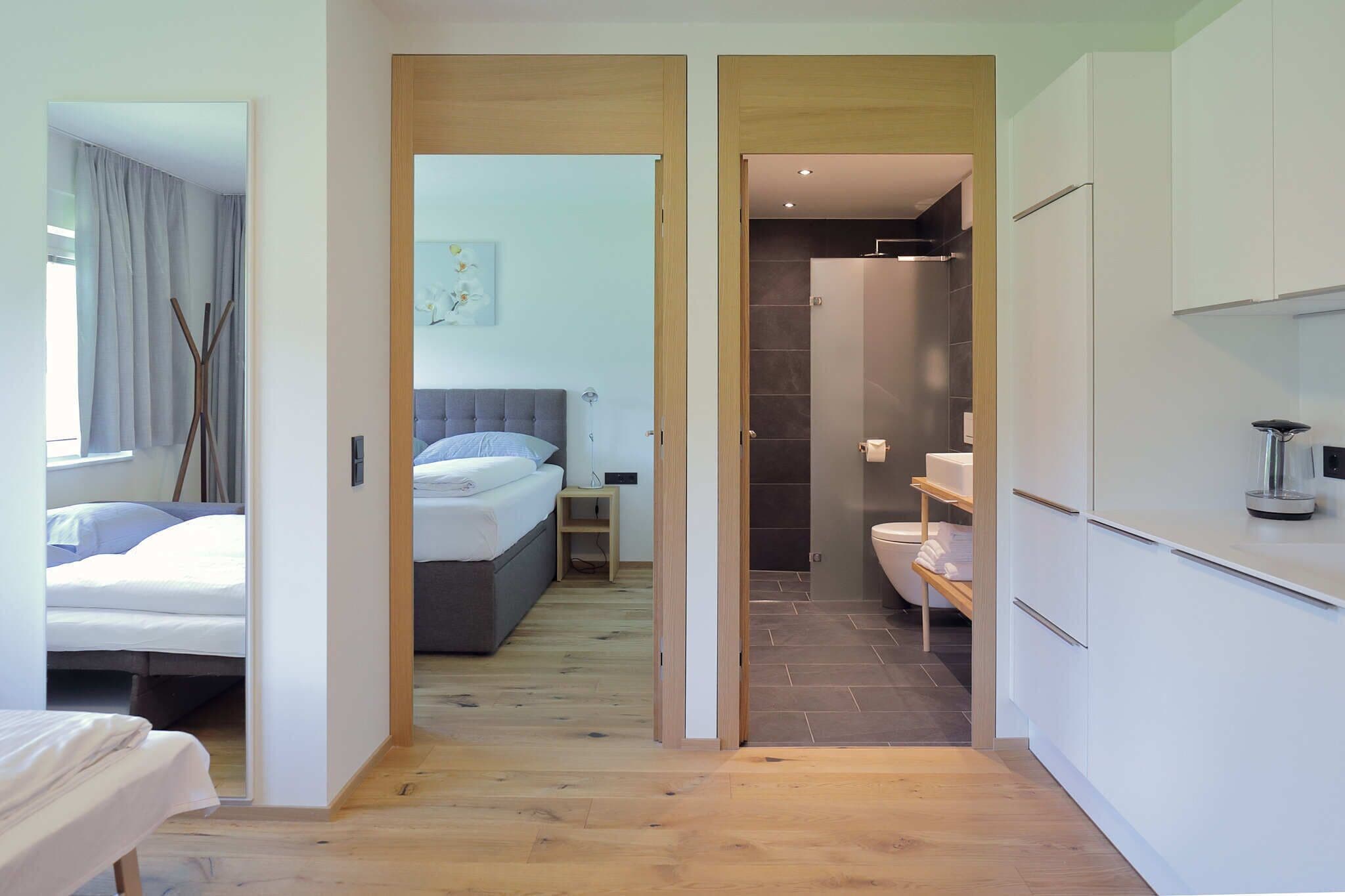A modern hotel room with a bed, bedside table, and a bathroom with a shower and toilet.