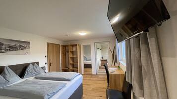 Un dormitorio con cama, escritorio, silla, armario y televisor.