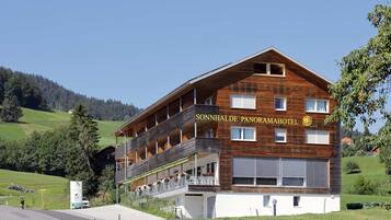 Un hotel de dos pisos con fachada de madera, balcones y un cartel que dice "SONNHALDE PANORAMAHOTEL".
