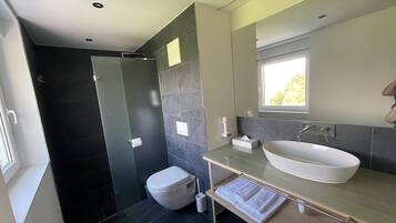 A modern bathroom with a large sink, a toilet, and a shower area.