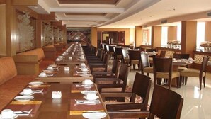 Une longue table à manger avec des chaises, un canapé et un mur décoratif.