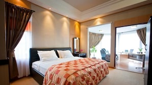 A hotel room with a large bed, a desk, and a chair.