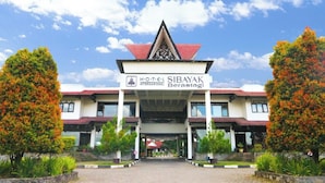 The entrance to Hotel SIBAYAK Berastagi with a traditional architectural design, featuring a prominent entrance canopy and symmetrical landscaping.