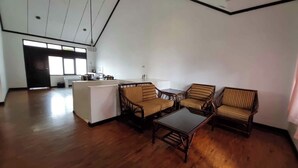 A spacious living area with a wooden floor, a central coffee table, and four striped sofas. A kitchen area is visible in the background.