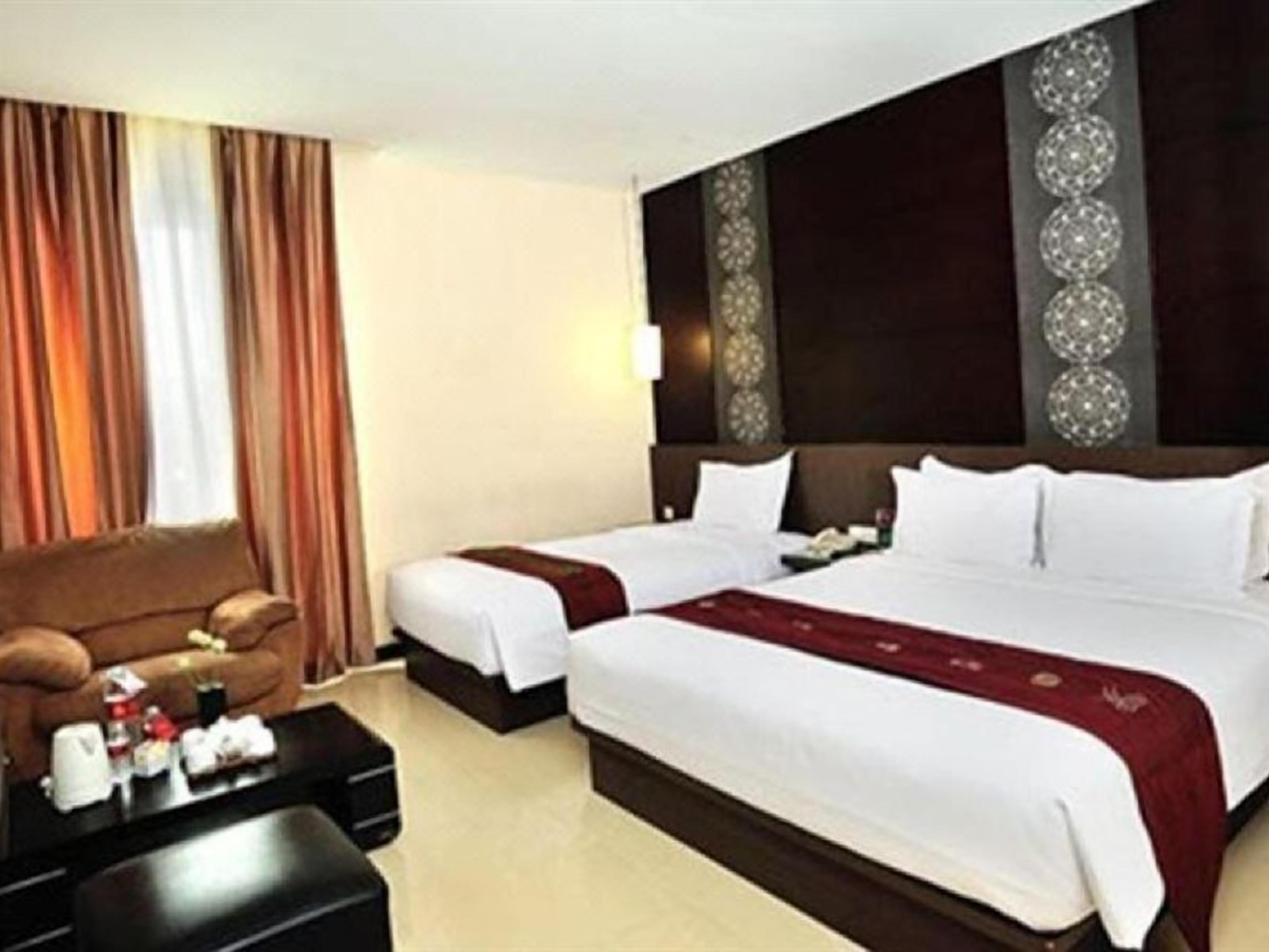A hotel room with two beds, a sofa, a coffee table, and a decorative wall panel.