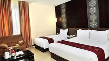 A hotel room with two beds, a sofa, a coffee table, and a decorative wall panel.