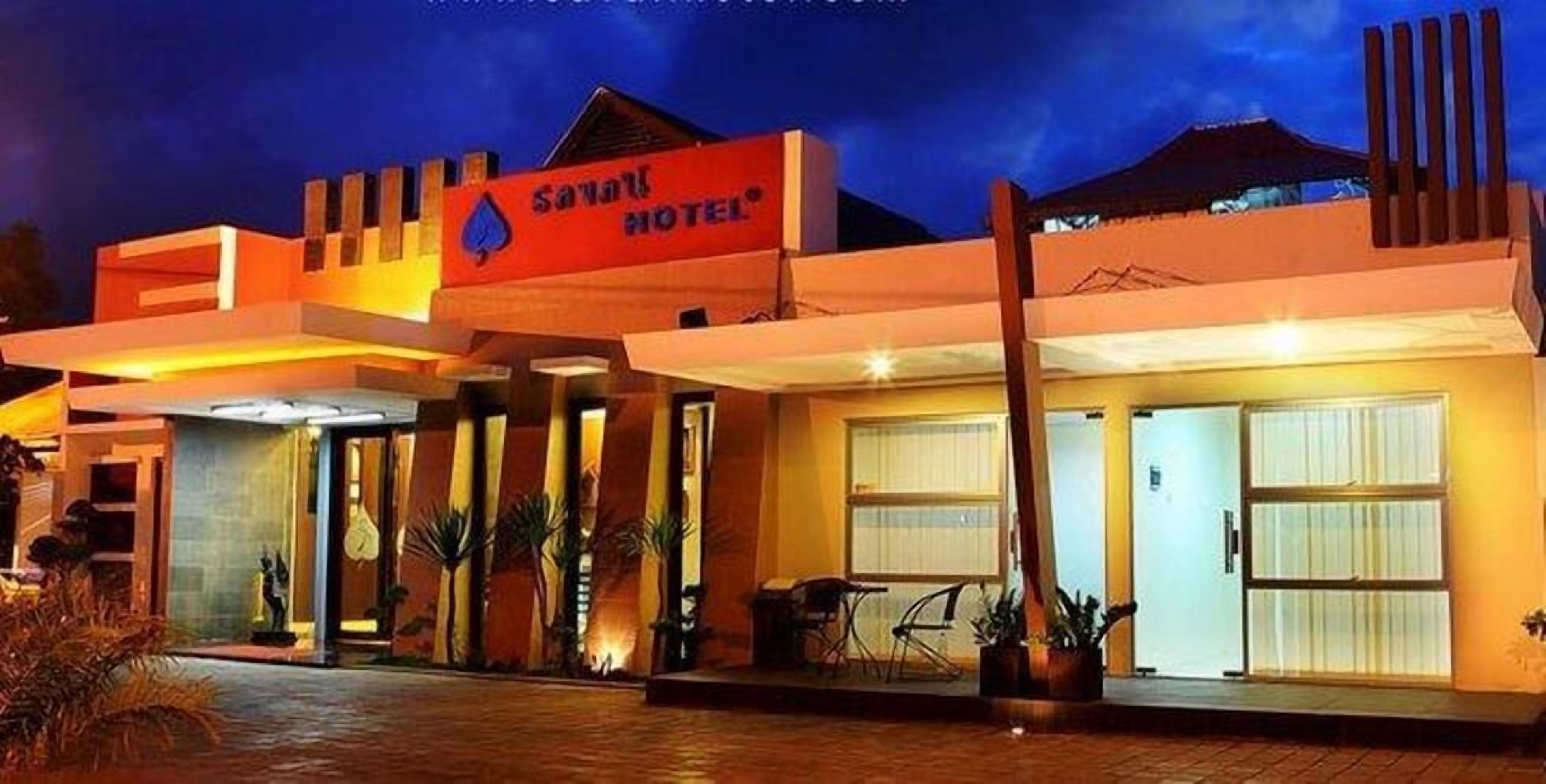 A modern hotel with a prominent sign, a covered entrance, and a well-lit facade.