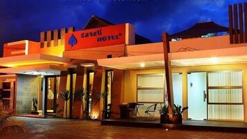 A modern hotel with a prominent sign, a covered entrance, and a well-lit facade.
