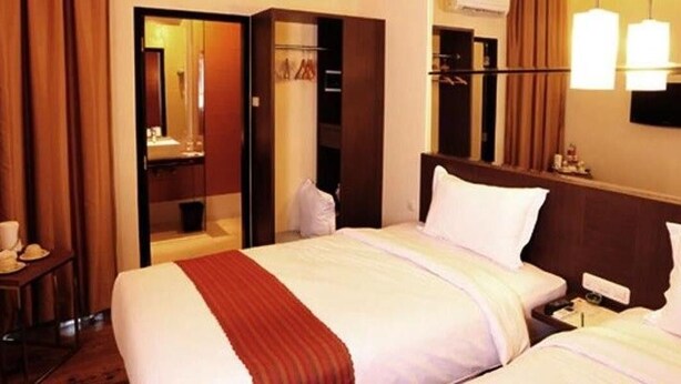 Une chambre d’hôtel comprenant un lit, des tables de chevet, une armoire et un miroir.