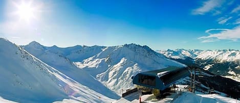 Un paisaje montañoso cubierto de nieve, con un telesilla y un edificio de techo inclinado.