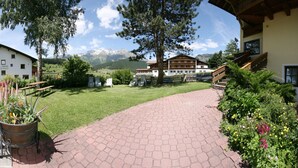 A hotel with a paved pathway leading to a building with a wooden staircase. - Pension Tirol (Nauders)