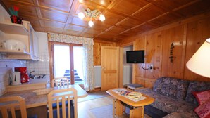 Interior de una cabaña de madera con cocina, comedor y sala de estar.