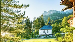 Una iglesia con tejado azul rodeada de exuberante vegetación y montañas al fondo.