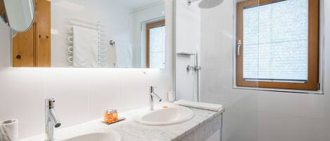 Ein modernes Badezimmer mit zwei Waschbecken, einem großen Spiegel und einer Dusche.
