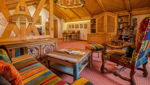 Un interior acogedor y rústico con vigas de madera, una araña, un sillón colorido y un comedor.