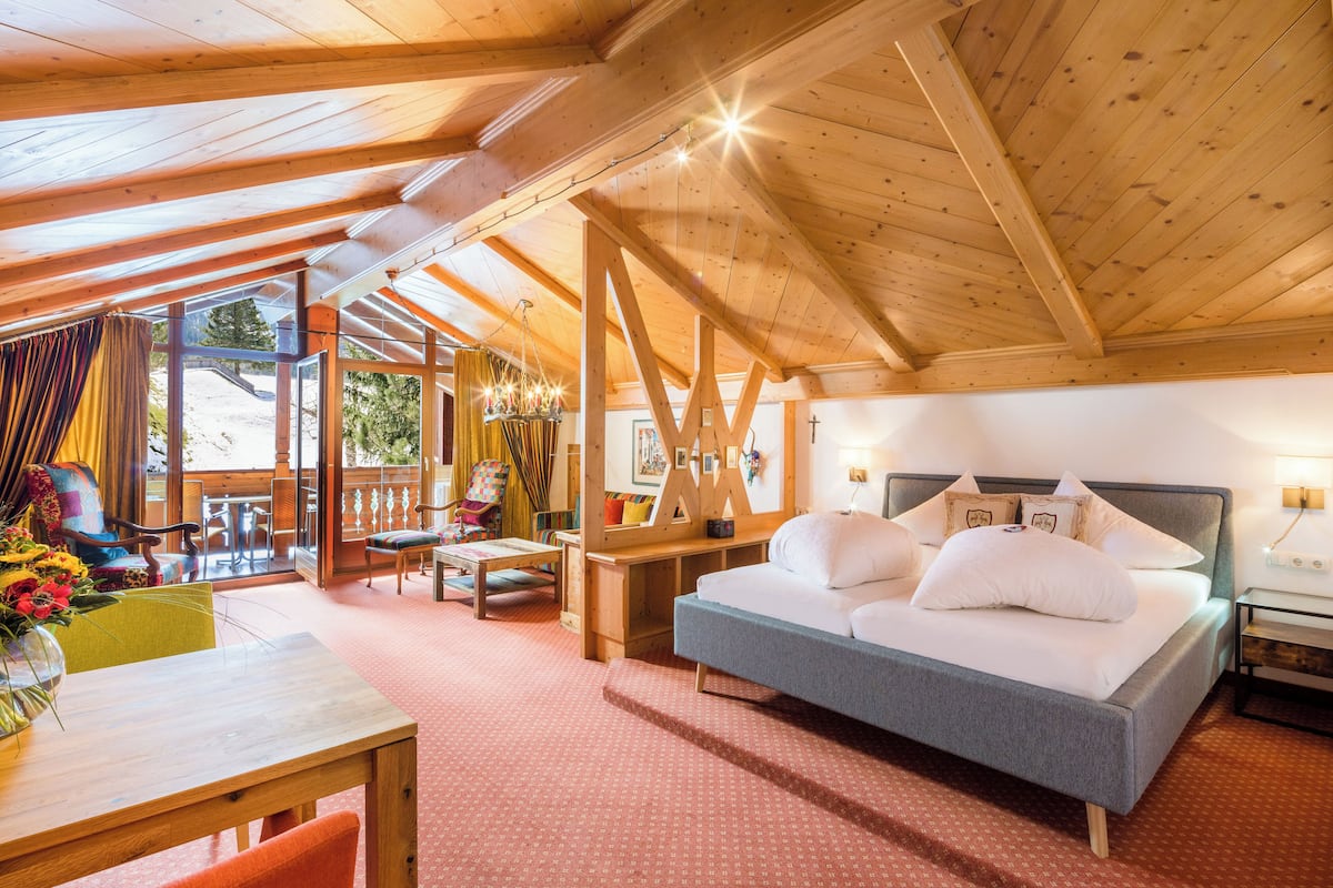 Una habitación acogedora con cama, una mesa con sillas y un balcón con vistas al exterior.