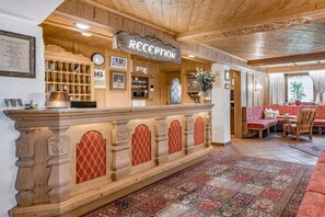 Una zona de recepción con un mostrador de madera, un reloj y un panel informativo en la pared.