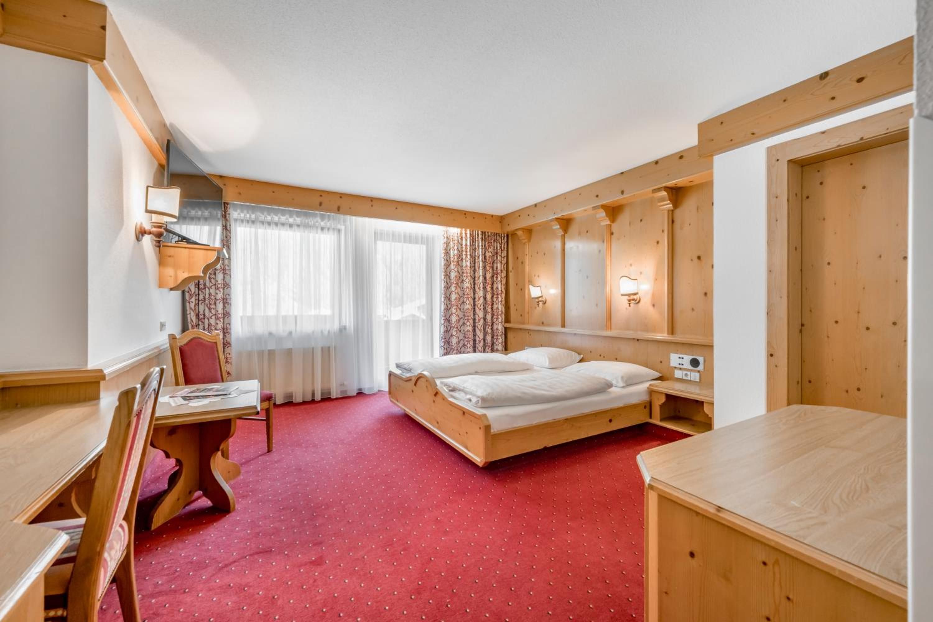 A hotel room with a wooden bed, a desk, and a chair.