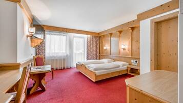 A hotel room with a wooden bed, a desk, and a chair.