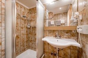 A bathroom with a shower, a sink, and a mirror.