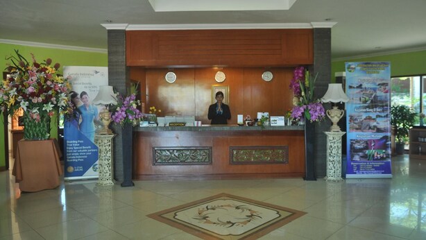 A reception desk with a clock, a framed picture, and a floral arrangement. - Tanjung Pesona Beach Resort and Spa (Sungai Liat)