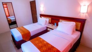 A hotel room with two beds, a nightstand with a phone, and a mirror. - Tanjung Pesona Beach Resort and Spa (Sungai Liat)