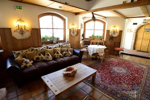 Quarto de hotel acolhedor com sofá de couro, mesa de centro de madeira e um tapete estampado.