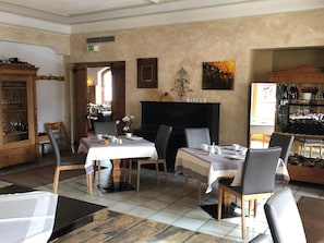 Un comedor con dos mesas dispuestas para comidas, una chimenea y una vinoteca.