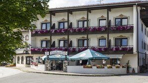 A multi-story building with balconies adorned with flowers, a sign for 'Gradwirt', and outdoor seating with umbrellas. - Hotel Gasthof Gradlwirt (Niederndorf)