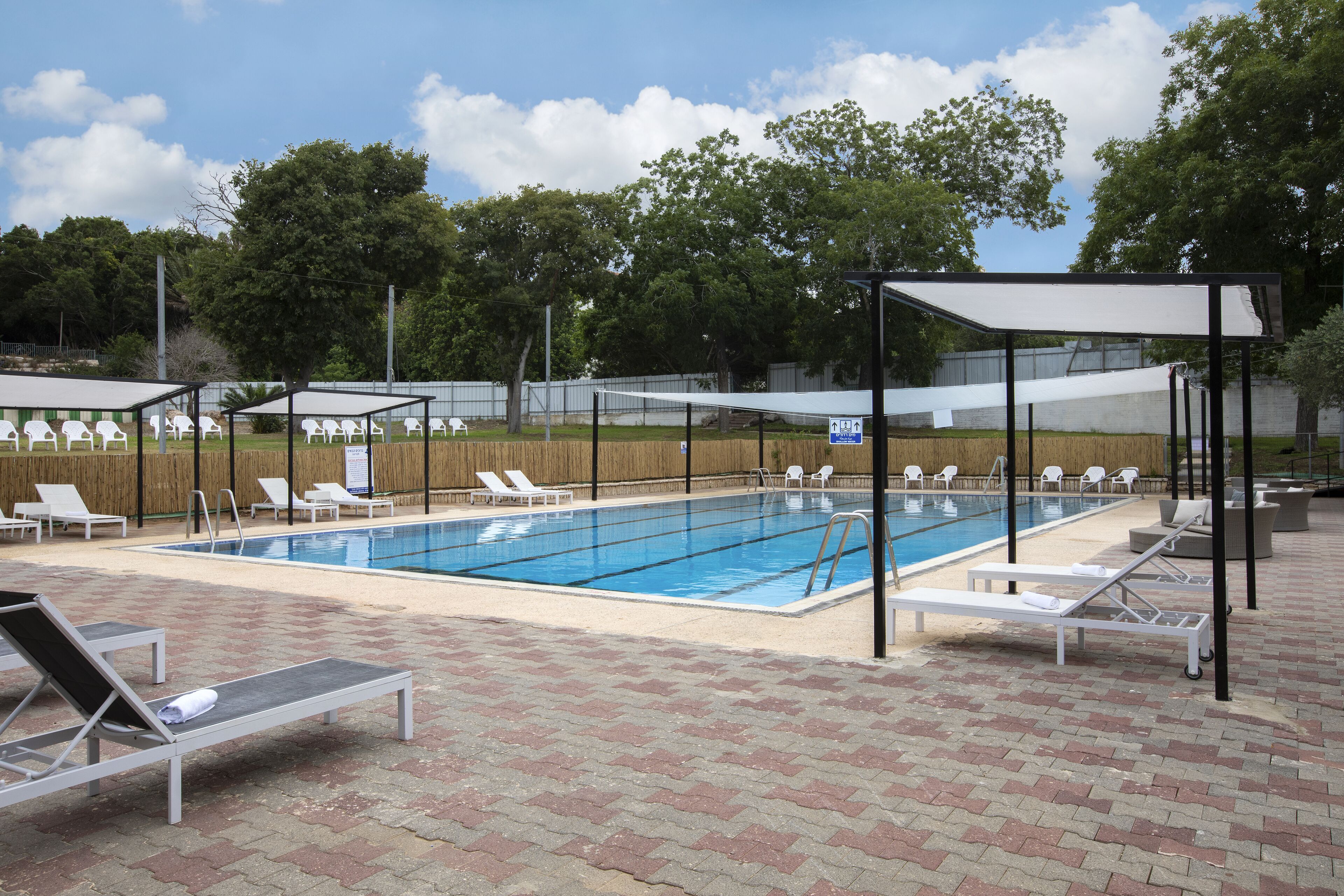 Una piscina con sillones de descanso y sombrillas.