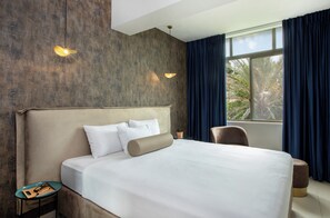 Une chambre d’hôtel avec un grand lit, une table de chevet, une chaise et une fenêtre avec des rideaux.