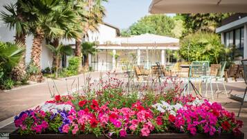A flower bed with various colorful flowers in front of a building with outdoor seating.