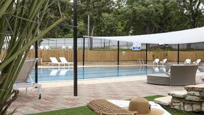 A pool area with lounge chairs, a covered seating area, and a table with a hat and bag. - Eden Inn (Zikhron Ya'aqov)